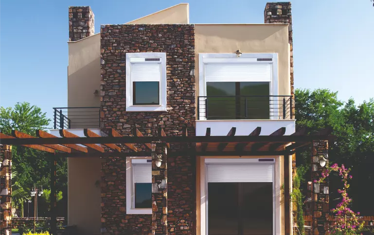 Vue d'une maison et de son jardin équipée de volets roulants solaires de la marque FLIP, fabricant français de volets roulants