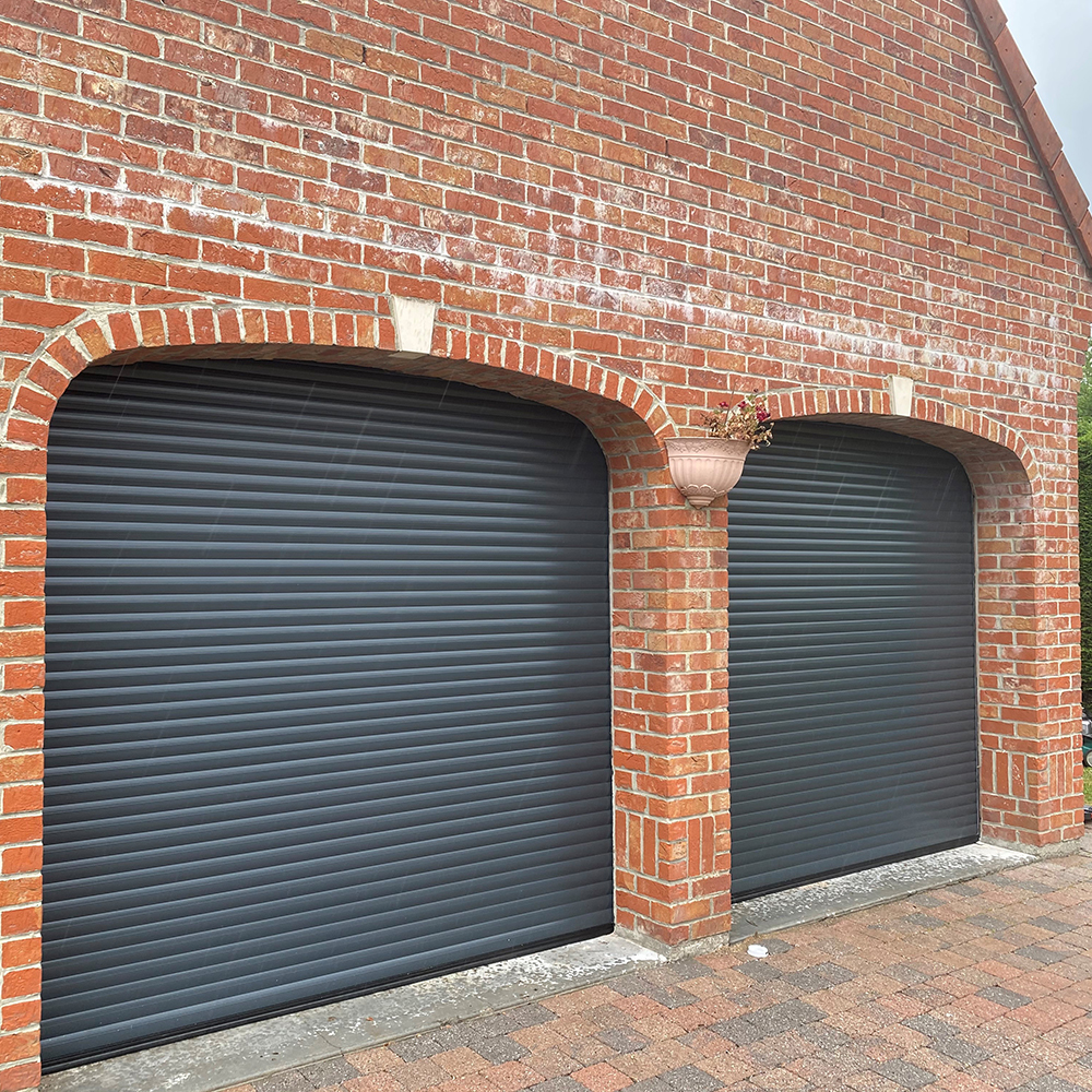 Double porte de garage enroulable Dooralux noir sur un mur en brique rouge