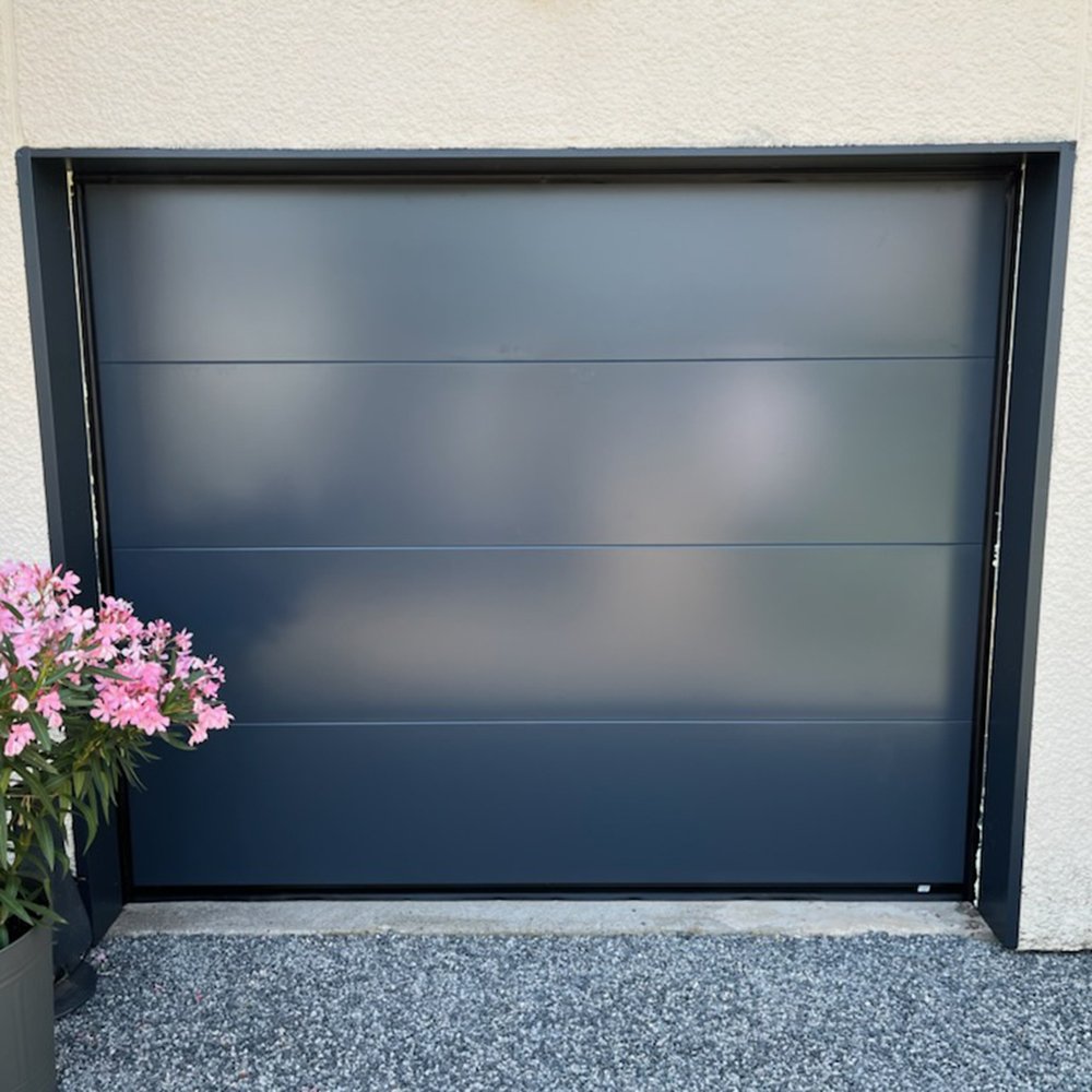 Porte de garage sectionnelle plafond sans rainure bleu foncé avec un pot de fleur devant