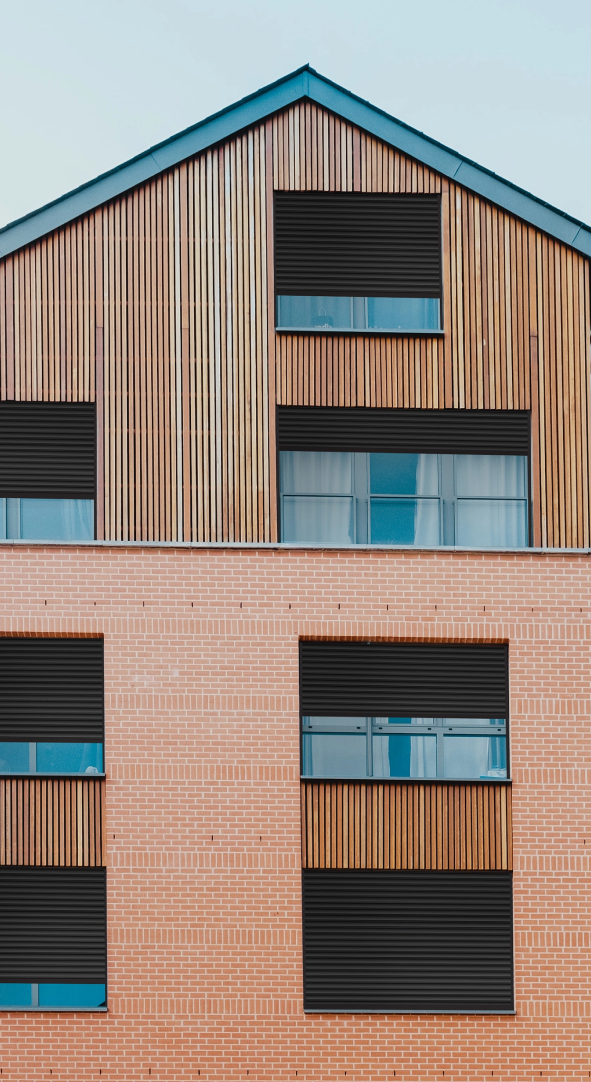 Immeuble moderne en brique et bois avec des volets roulants tradilux noir de la marque Flip