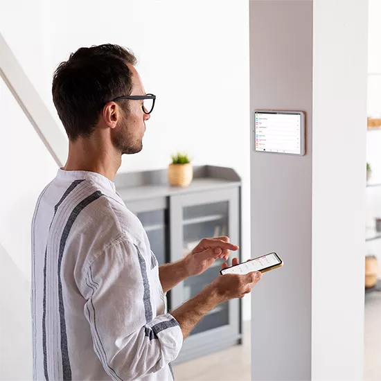 Homme qui manipule son téléphone pour régler son appareil domotique