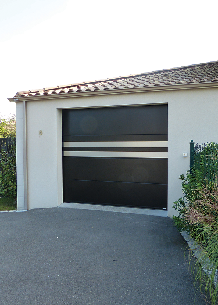 Porte de garage sectionnelle plafond noire avec des décorations sur un mur d'une maison blanche