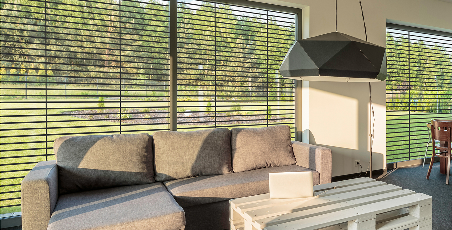 Vue interieur d'un salon avec des murs beige, devant des brise soleil orientable noir