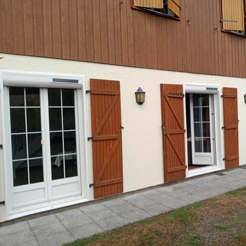 Porte de maison vue de l'extérieur avec volet roulants astrosun blancs donnant sur une terrasse